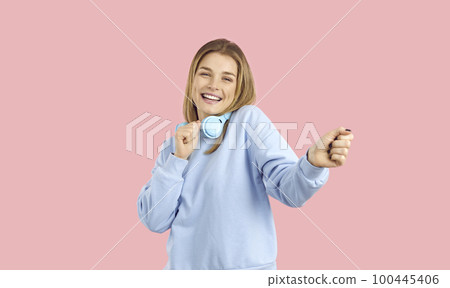 Portrait of cheerful positive dancing teenage girl who moves with headphones around her neck. 100445406
