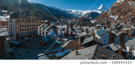 Aerial view on Zermatt Valley town and Matterhorn Peak in the background in the morning in Switzerland. Magical Swiss town with no cars and electric trains going up the mountains. Aerial view on Zermatt Valley town and Matterhorn Peak in the background in the morning in Switzerland. Magical Swiss town with no cars and electric trains going up the mountains. 100445433