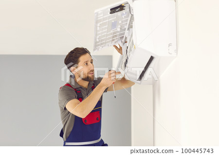 Worker standing on ladder and installing new modern white air conditioner on wall at home Worker standing on ladder and installing new modern white air conditioner on wall at home 100445743
