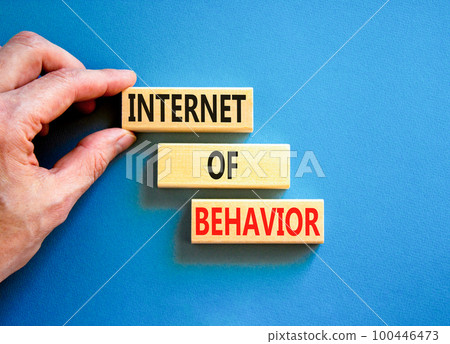 Internet of behavior symbol. Concept words Internet of behavior on wooden block on a beautiful blue table blue background. Businessman hand. Business Internet of behavior concept. Copy space. Internet of behavior symbol. Concept words Internet of behavior on wooden block on a beautiful blue table blue background. Businessman hand. Business Internet of behavior concept. Copy space. 100446473