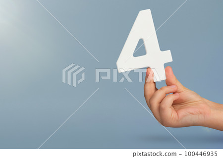 number four in hand. Hand holding white number 4 on blue background with copy space. Concept with number four. Birthday 4 years, fourth grade, four day work week 100446935