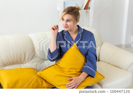 Fun minded woman wear pajama she sitting on couch use rest relax spend time in living room lounge home in own room hotel wake up 100447120
