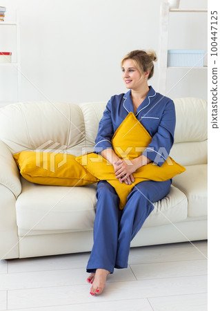 Cute female model in pajama enjoying morning. Pleasant woman sitting on sofa. Good mood Cute female model in pajama enjoying morning. Pleasant woman sitting on sofa. Good mood 100447125