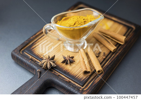 spicy dry turmeric with cinnamon sticks on a wooden board spicy dry turmeric with cinnamon sticks on a wooden board 100447457