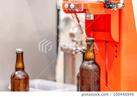 capping beer bottles in a brewery 100448949