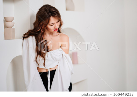 portrait of an attractive woman in a white romantic top with open shoulders. portrait of an attractive woman in a white romantic top with open shoulders. 100449232