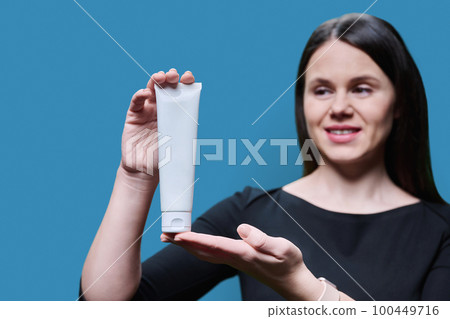 Close-up of white clean tube with cosmetic product in hands of woman Close-up of white clean tube with cosmetic product in hands of woman 100449716
