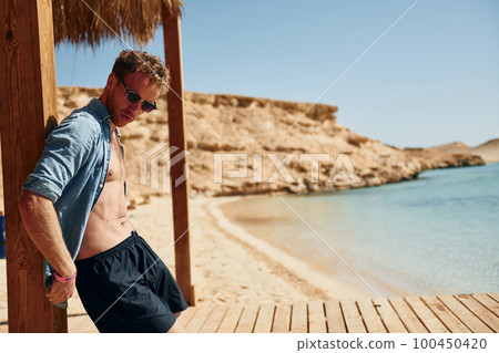 Clear water. Young european man have vacation and enjoying free time on the beach of sea 100450420