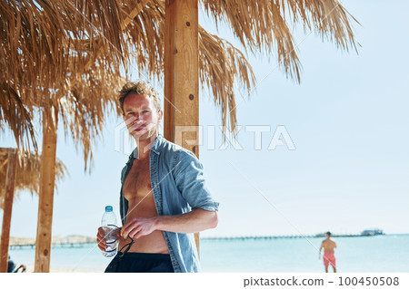 Posing for a camera. Young european man have vacation and enjoying free time on the beach of sea 100450508