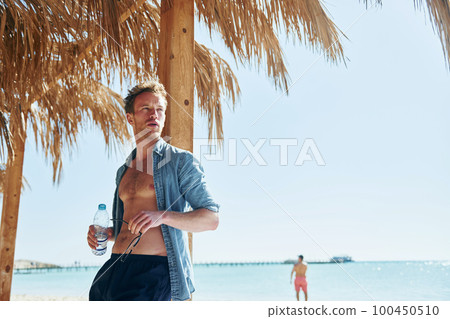 Posing for a camera. Young european man have vacation and enjoying free time on the beach of sea 100450510