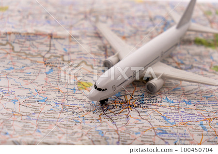 Close up detail of a miniature passenger airplane on a colorful map focusing on Dallas Fort Worth through selective focus, background blur.  100450704