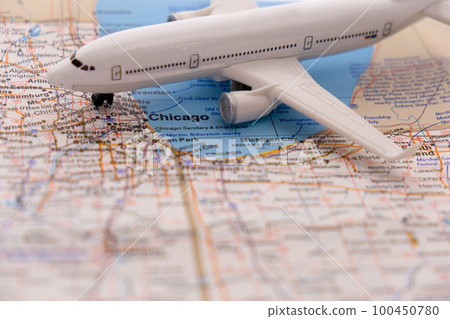 Miniature passenger airplane on a detailed colorful map focusing on Chicago, Illinois through selective focus, background blur 100450780