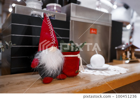 Closeup of santa claus figurine and plant with red decor displayed on wooden table by equipment in luxury hotel 100451236
