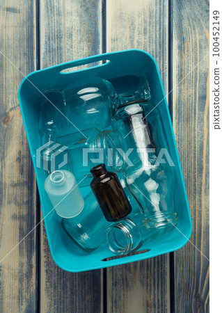 Vertical blue plastic container full of transparent plastic and glass bottles on wooden table. Sustainable development Vertical blue plastic container full of transparent plastic and glass bottles on wooden table. Sustainable development 100452149