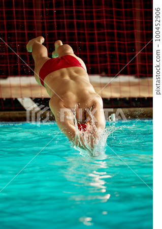 A male swimmer dives into the pool with his head into the water, the start of the swim in the pool. 100452906