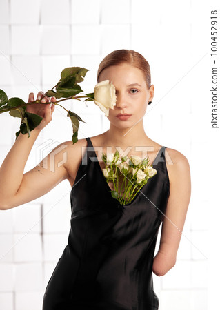 Beautiful young with special needs woman with flowers in her hand holding a flower, woman in black dress. Diversity women with disability and flowers. Beautiful young with special needs woman with flowers in her hand holding a flower, woman in black dress. Diversity women with disability and flowers. 100452918