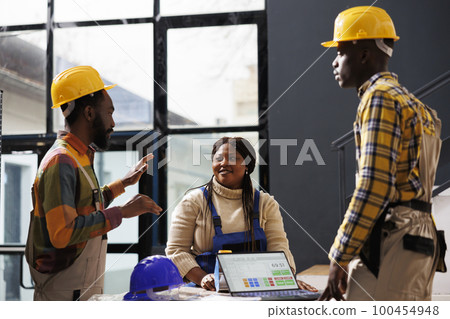 African american warehouse employees checking items listing on laptop and talking at work. All black shipment managers coworkers team picking online client order and looking at purchase checklist 100454948
