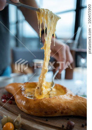 person mixing suluguni cheese and egg yolk in georgian adjarian khachapuri 100455900