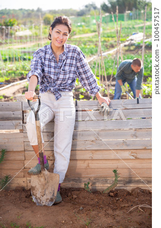 Girl in white jeans on veranda with shovel on background of garden beds Girl in white jeans on veranda with shovel on background of garden beds 100457517