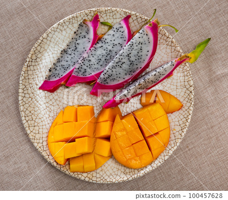 Plate of slices of ripe sweet and juicy mango and pitaya 100457628
