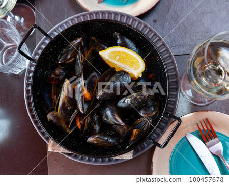 Steamed mussels in shells with lemon in metal serving pan Steamed mussels in shells with lemon in metal serving pan 100457678