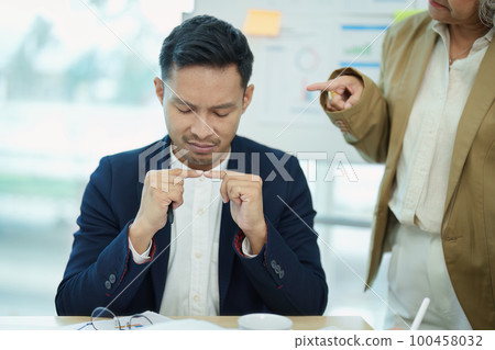 An image of an Asian male employee looking worried and sad about being scolded by his boss for failing to meet sales targets, concept of disappointment and failure in his career. An image of an Asian male employee looking worried and sad about being scolded by his boss for failing to meet sales targets, concept of disappointment and failure in his career. 100458032