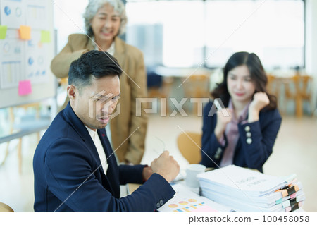 An image of an Asian male employee looking worried and sad about being scolded by his boss for failing to meet sales targets, concept of disappointment and failure in his career. 100458058