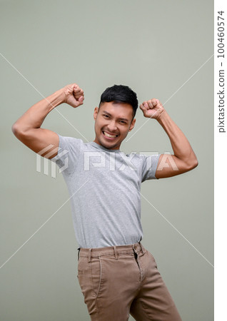 Happy Asian man raising hand up, rejoicing, dancing with joy, yes gesture, winning 100460574