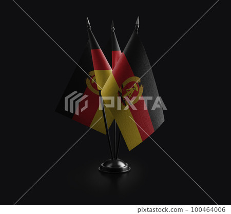 Small national flags of the DDR on a black background 100464006