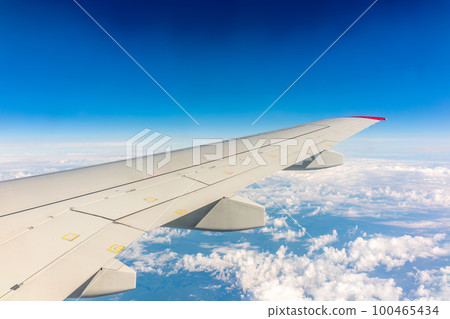 View from the airplane window at a beautiful cloudy sky and the airplane wing View from the airplane window at a beautiful cloudy sky and the airplane wing 100465434