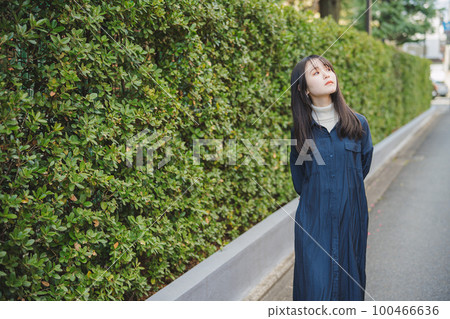 Girl walking in front of green plants 100466636