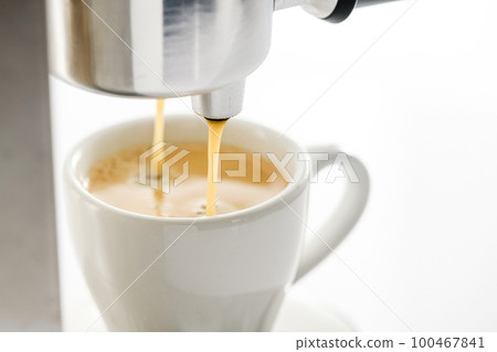 Espresso machine pouring strong fresh coffee into a ceramic cup Espresso machine pouring strong fresh coffee into a ceramic cup 100467841