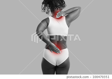 Young woman who suffers from spinal pain is massaging her neck and lower back areas 100470351