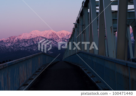 被夕陽和北阿爾卑斯茂胜山的雪景染紅的常願寺川大日橋 被夕陽和北阿爾卑斯茂胜山的雪景染紅的常願寺川大日橋 100471440