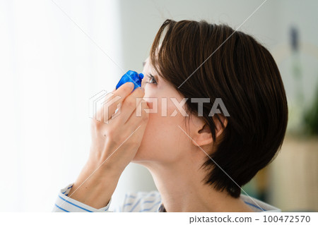 Young woman taking eye drops hay fever image 100472570