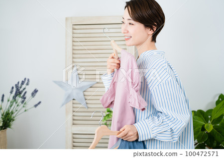 Fashion image of a young woman choosing clothes in front of a mirror 100472571