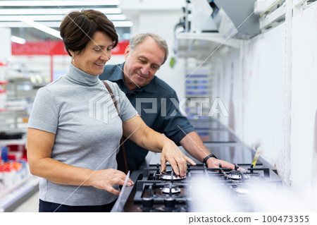 Mature couple choosing stove in home appliances department in grocery store Mature couple choosing stove in home appliances department in grocery store 100473355
