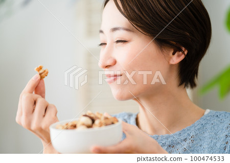 Young woman eating mixed nuts Eating and drinking image Young woman eating mixed nuts Eating and drinking image 100474533