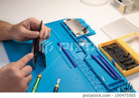 Repairman fixing broken smartphone with tools. Repairman fixing broken smartphone with tools. 100475885