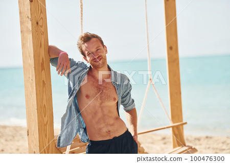 Shows body. Young european man have vacation and enjoying free time on the beach of sea Shows body. Young european man have vacation and enjoying free time on the beach of sea 100476300
