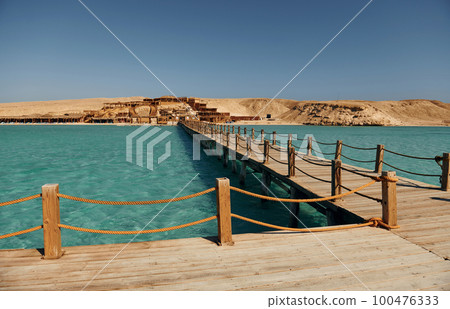 Majestic view of wooden bridge that is on the sea. Island far away 100476333