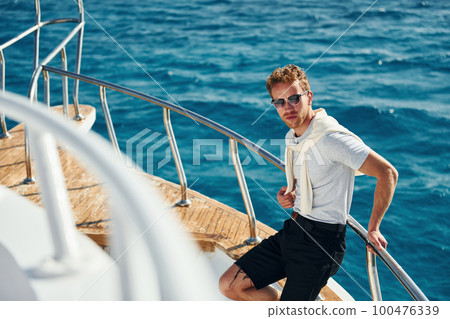 Posing for a camera. Young male tourist is on the yacht on the sea. Conception of vacation Posing for a camera. Young male tourist is on the yacht on the sea. Conception of vacation 100476339