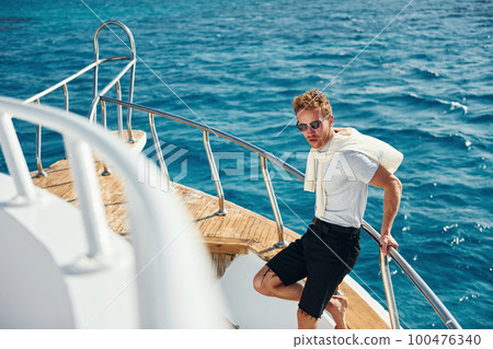 Posing for a camera. Young male tourist is on the yacht on the sea. Conception of vacation Posing for a camera. Young male tourist is on the yacht on the sea. Conception of vacation 100476340
