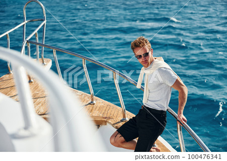 Posing for a camera. Young male tourist is on the yacht on the sea. Conception of vacation Posing for a camera. Young male tourist is on the yacht on the sea. Conception of vacation 100476341