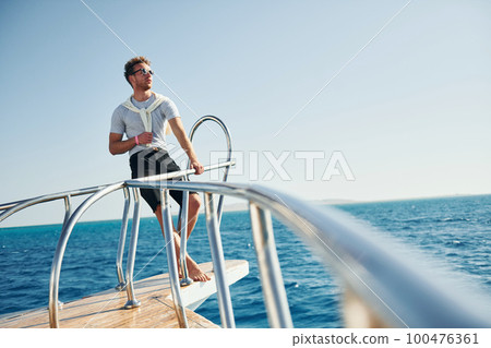 Posing for a camera. Young male tourist is on the yacht on the sea. Conception of vacation Posing for a camera. Young male tourist is on the yacht on the sea. Conception of vacation 100476361