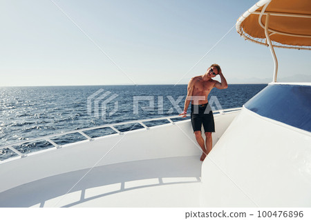 In sunglasses. Young male tourist is on the yacht on the sea. Conception of vacation 100476896