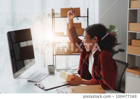 American African entrepreneur smile and use a mobile phone to check online order. Successful SME entrepreneur concept American African entrepreneur smile and use a mobile phone to check online order. Successful SME entrepreneur concept 100477168