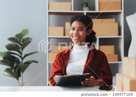 American African entrepreneur smile and working to check online order. Successful SME entrepreneur concept American African entrepreneur smile and working to check online order. Successful SME entrepreneur concept 100477169