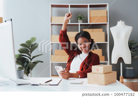 American African entrepreneur smile and use a mobile phone to check online order. Successful SME entrepreneur concept American African entrepreneur smile and use a mobile phone to check online order. Successful SME entrepreneur concept 100477182