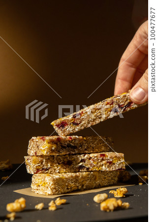 Woman takes Homemade Granola energy bar. Variety of protein granola breakfast bars, with nuts, raisins dried cherries and chocolate. Healthy nutrition eating Gluten free cereal dieting snack super Woman takes Homemade Granola energy bar. Variety of protein granola breakfast bars, with nuts, raisins dried cherries and chocolate. Healthy nutrition eating Gluten free cereal dieting snack super 100477677